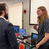 Man in suit talks to GVSU student